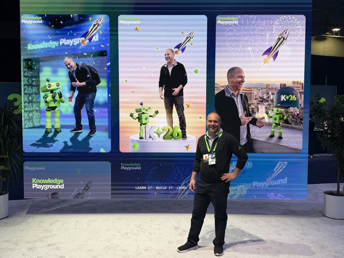 Erich Schindler standing in front of the Knowledge Playground video wall at ServiceNow Knowledge 2026, which shows three oversized photos of him.