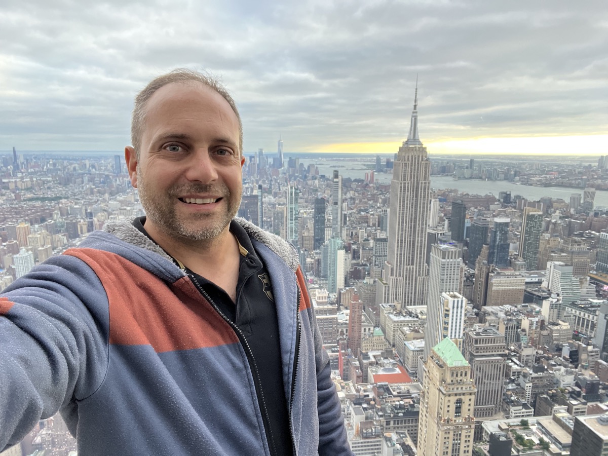 Selfie of Erich Schindler smiling above the Manhattan skyline, with the Empire State Building behind him.
