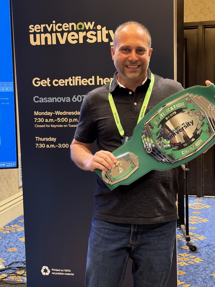 Erich Schindler grinning while holding a green ServiceNow University certification champion belt in front of a ServiceNow University banner.